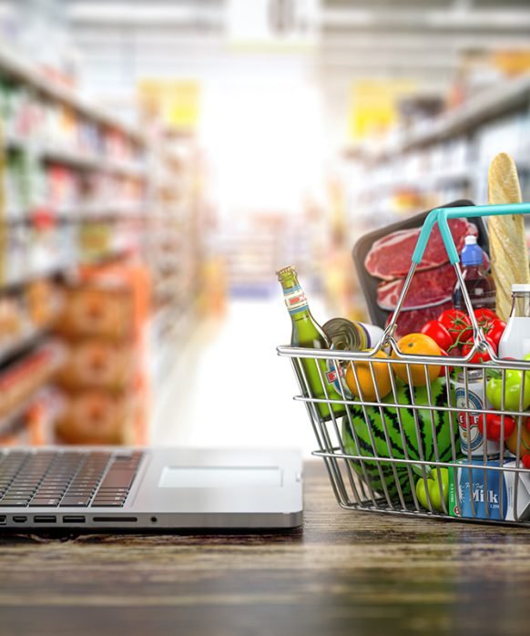 Grocery food buying online and delivery concept. Shopping basket full of food  and laptop on the shelf of supermarket. 3d illustration